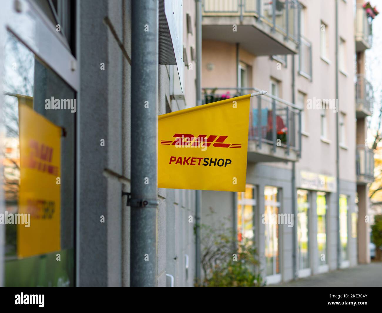 DHL Paketshop (DHL service shop) sign on a building exterior. Service of the Deutsche Post AG to send and receive shipments. Retail store in the city. Stock Photo