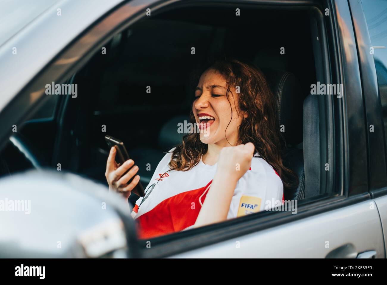 Peruvian soccer fan reacting with excitement to a soccer match by looking at his cell phone. Concept of people and sports. Stock Photo