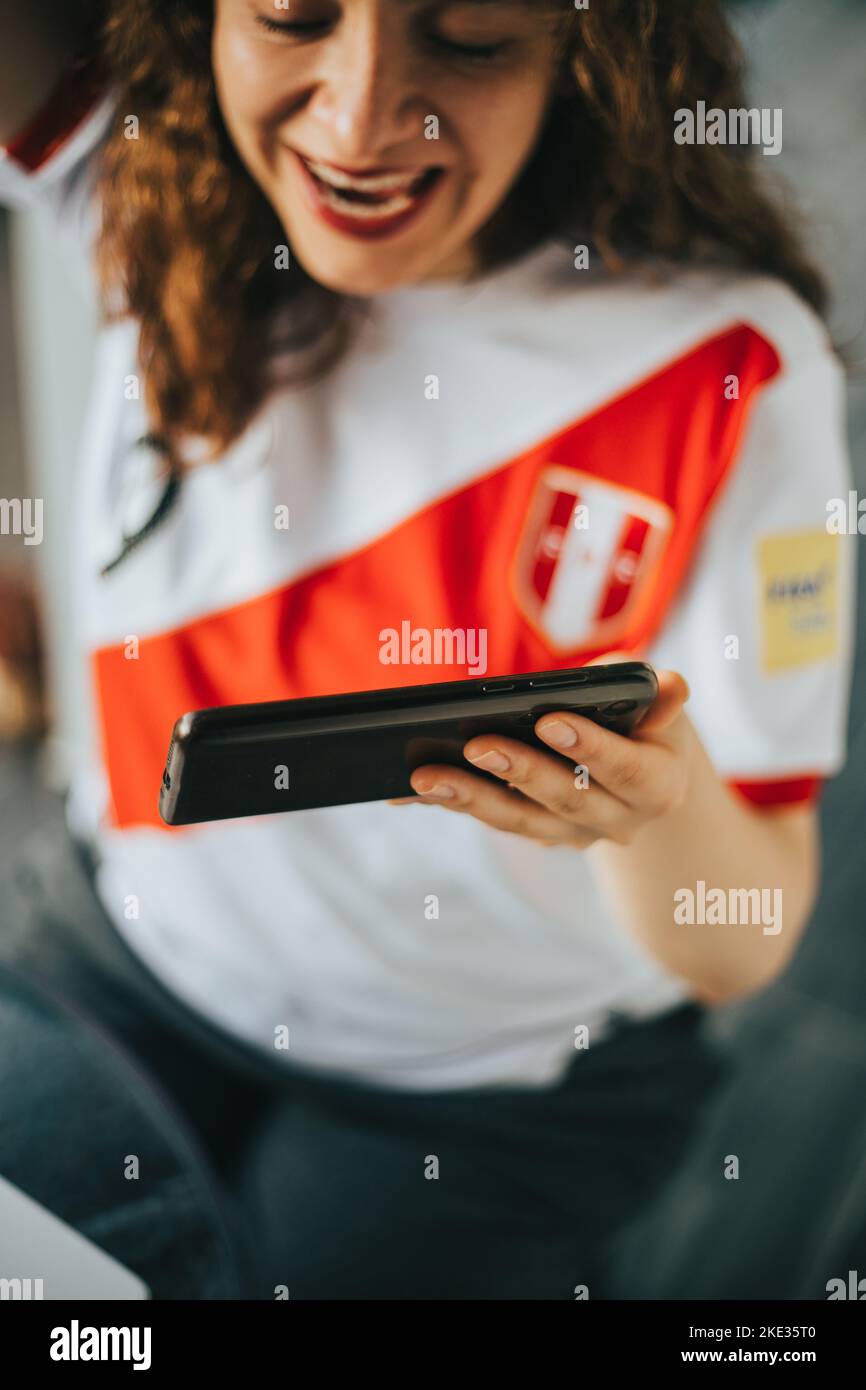 Peruvian soccer fan reacting with excitement to a soccer match by looking at his cell phone. Concept of people and sports. Stock Photo