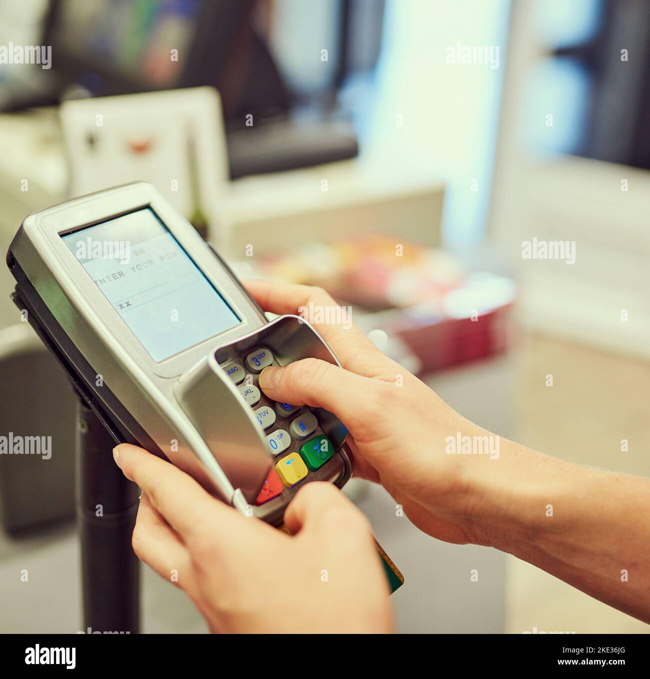 Enter your pin to complete your payment. Closeup shot of a person typing their pin number into a credit card machine at a grocery store. Stock Photo