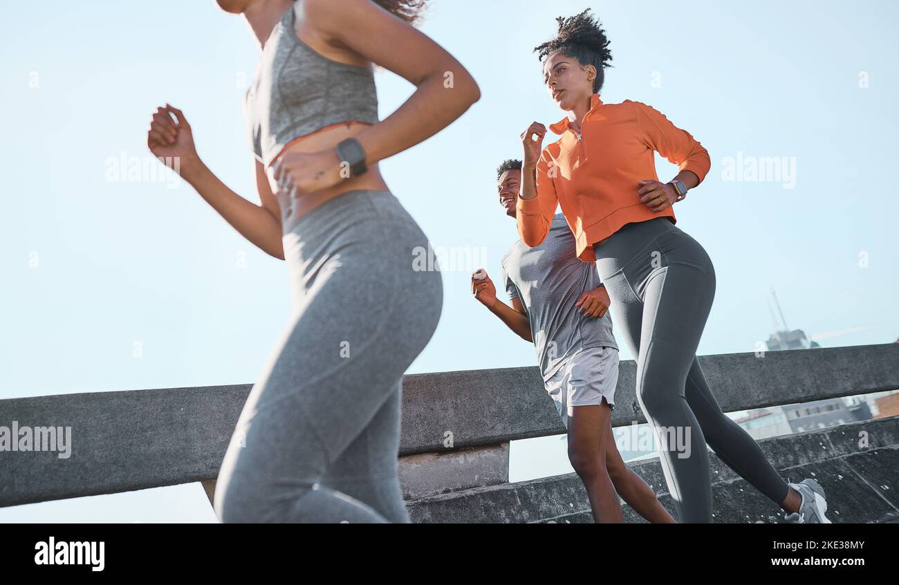 Women, black man and running in city fitness, workout or exercise for cardio health, wellness or marathon training. Sports people, friends or runner Stock Photo