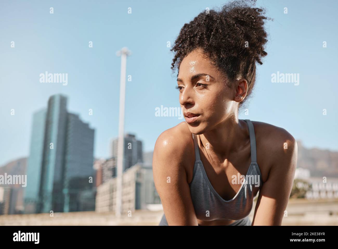 Fitness, runner and tired black woman in a city sweating from running exercise, cardio workout or training. Breathing, fatigue and sports athlete Stock Photo