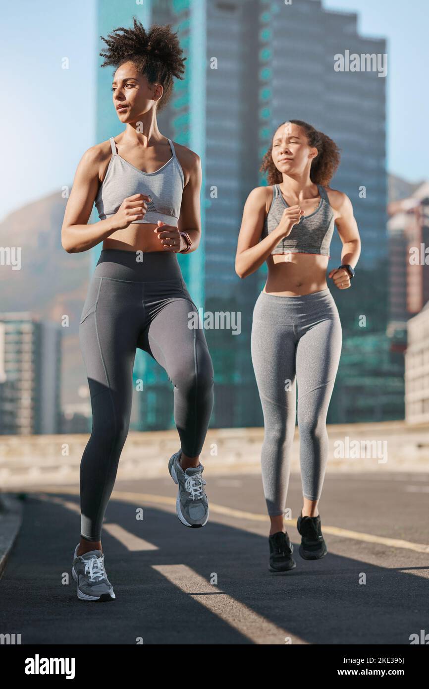 Women, fitness and running on city street or road in workout, training or exercise for cardio health, marathon or wellness. People, friends and runner Stock Photo