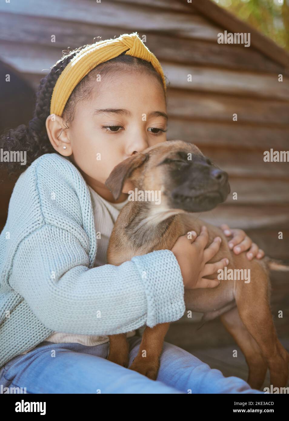 Child, pet animal and kiss for love, care and happiness for dog, fun friend or partner. Black girl outdoor for adoptoion with healthy rescue puppy for Stock Photo