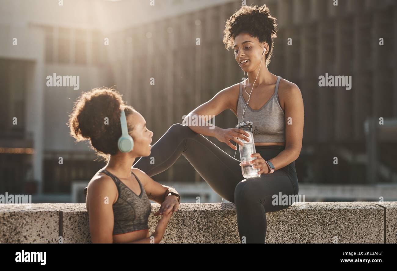 Headphones, fitness and black woman friends in city with water bottle, training gear and music for training motivation, team and social conversation Stock Photo
