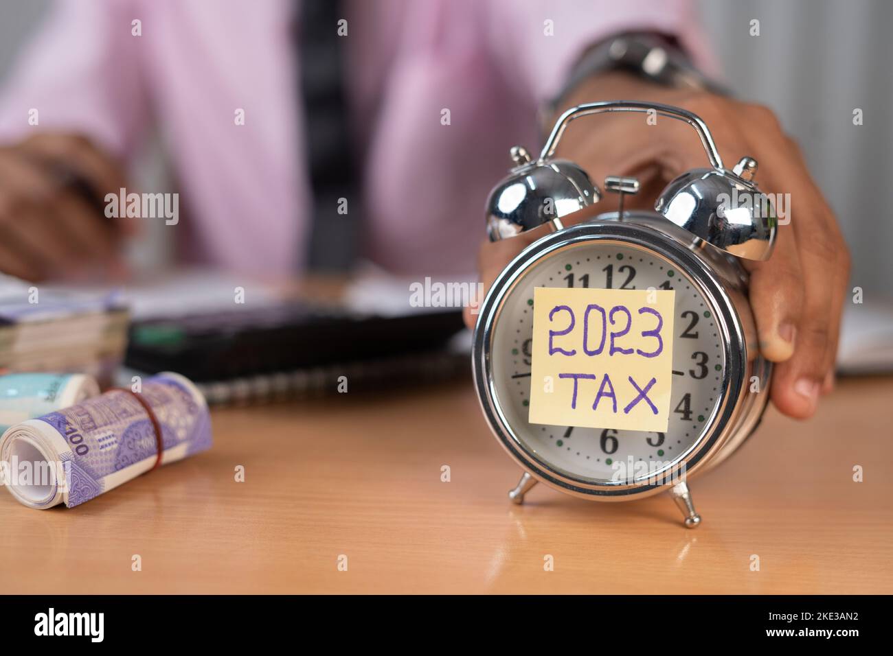 businessman placing timer with 2023 tax while calculating financial bills at office table - concept of financials and investment Stock Photo