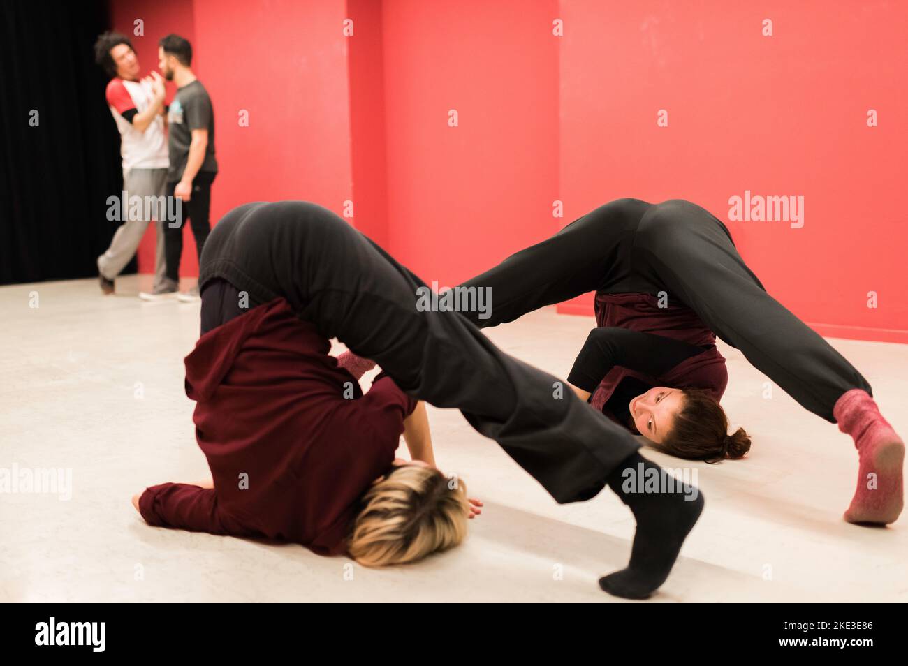 Two young fit women standing upside down and stretching legs in dance