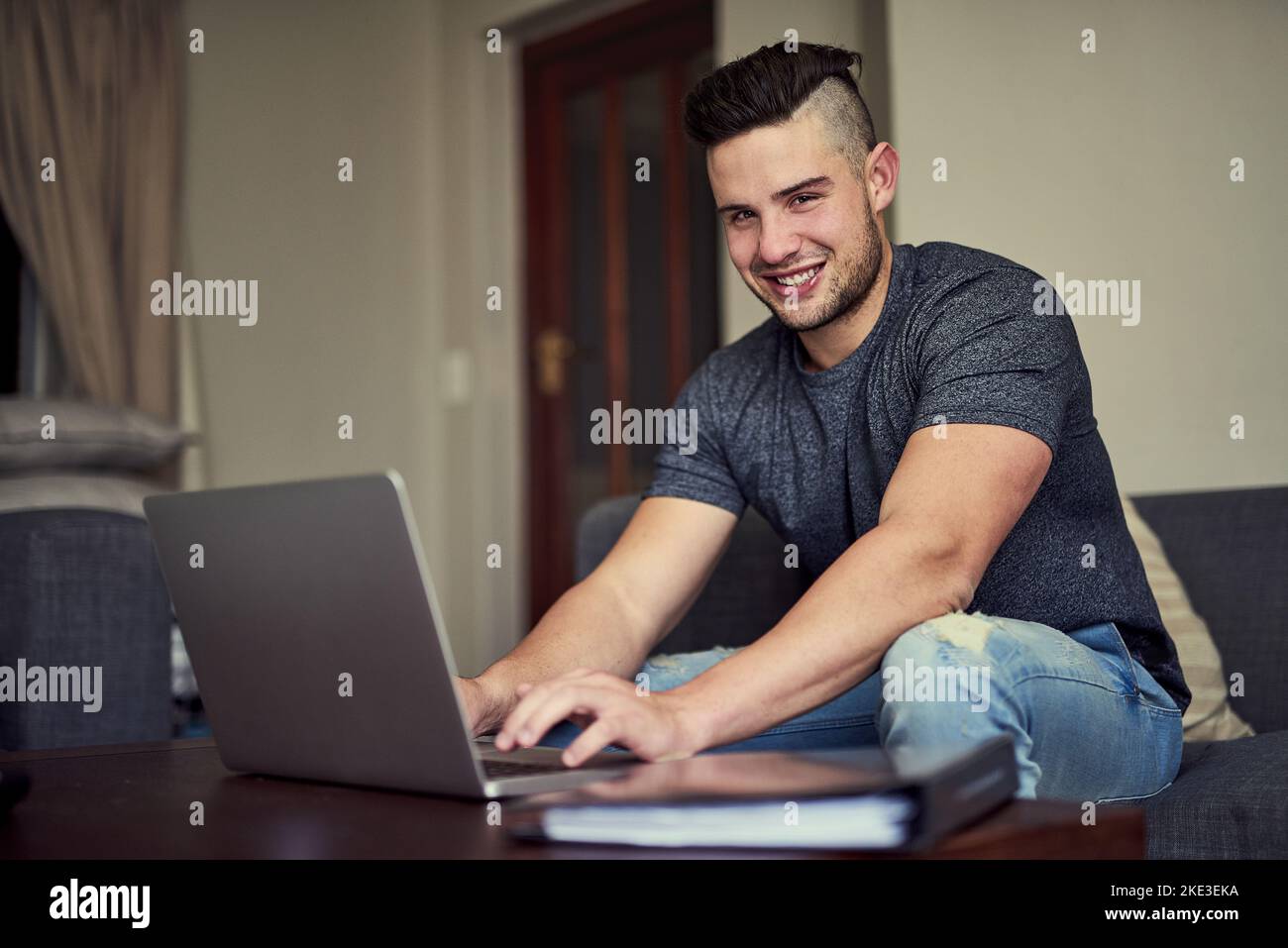 Work hard and make it happen. Portrait of a happy young man using his laptop to work from home. Stock Photo