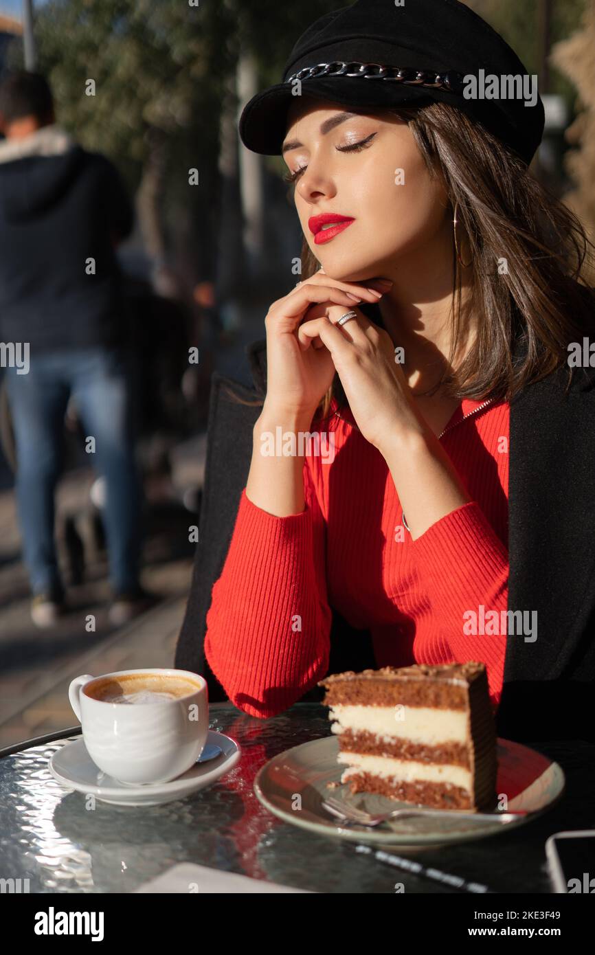 Satisfied girl breathing fresh air with a cup of coffee in cafe, enjoying sunshine with close eyes. Portrait Stock Photo