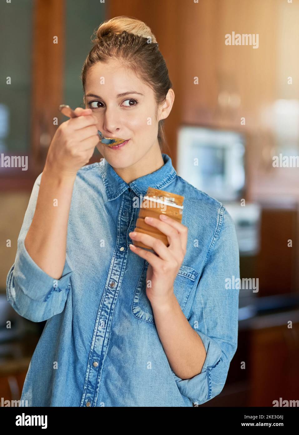 Joy straight from the jar. a young woman eating peanut butter out of
