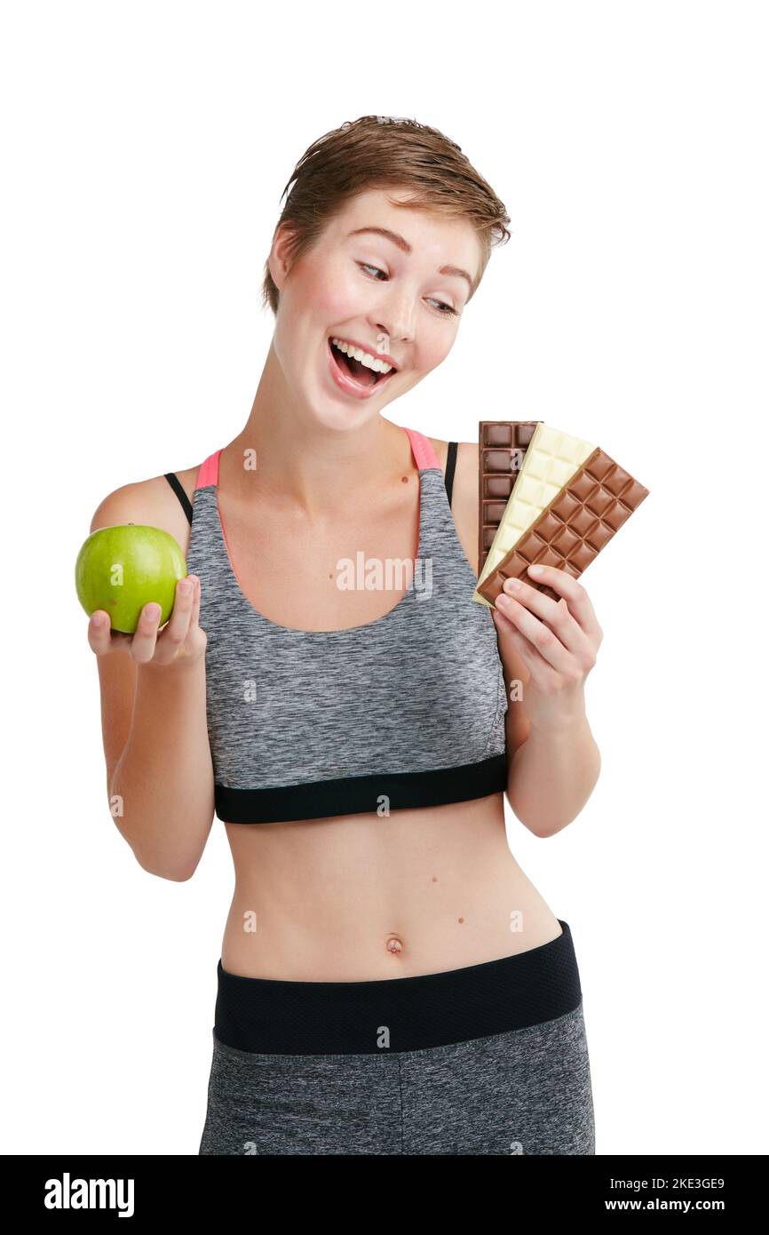 Make the healthy choice for a healthy life. Studio shot of a fit young woman deciding whether to eat chocolate or an apple against a white background. Stock Photo
