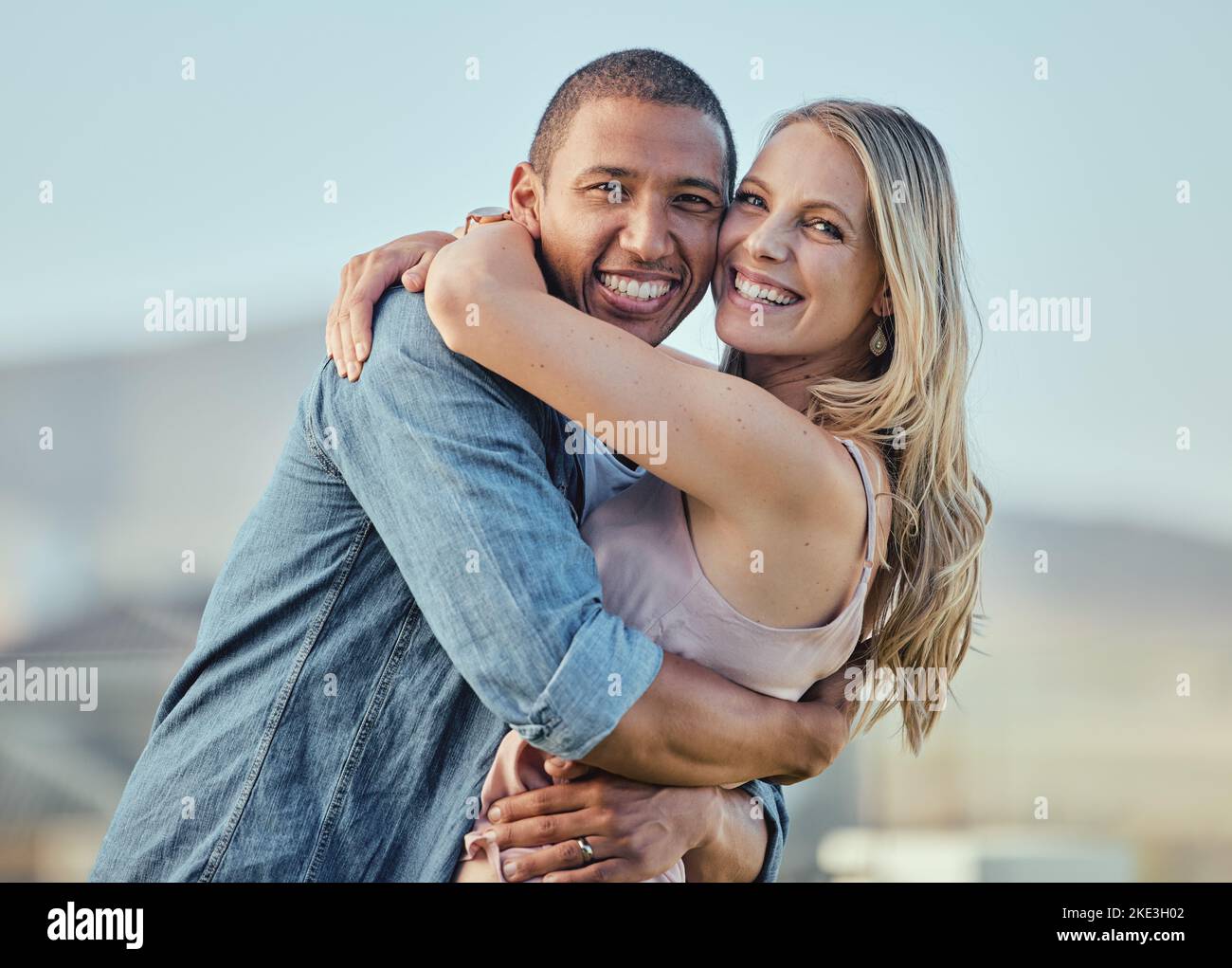 Happy interracial couple, hug and portrait smile for relationship happiness, travel or bonding in the outdoors. Man and woman hugging, smiling and Stock Photo
