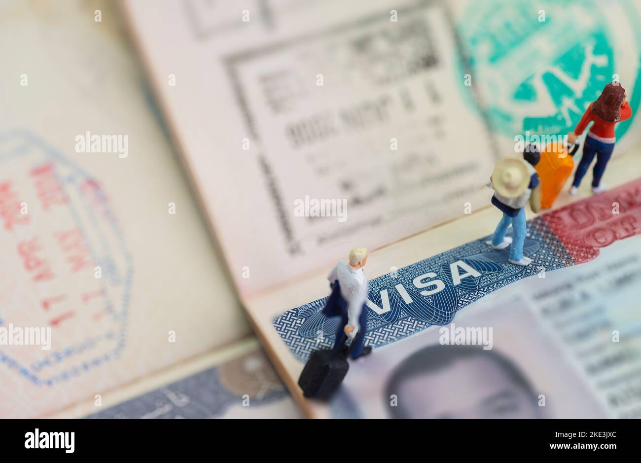 Miniature toys studio set up - expatriate business man and other travellers travel with visa on passport as background. Stock Photo