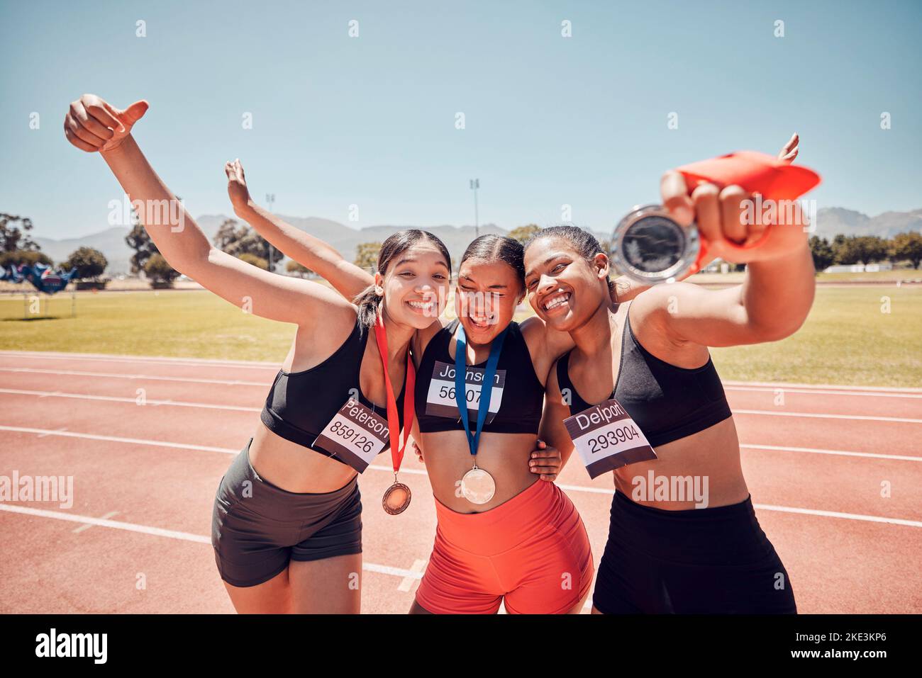 Medal, champion and women at a stadium for sports, running and celebration of winning marathon. Diversity, winner and athlete team with an award for Stock Photo