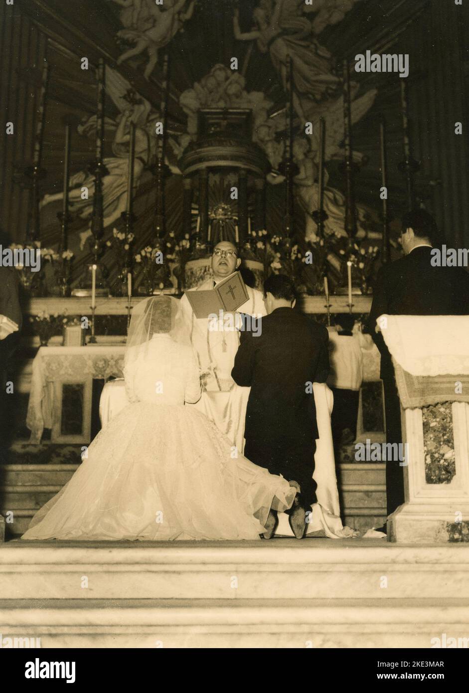 Wedding in a village in central Italy: The Bride and the Groom in the church in front of the priest, 1950s Stock Photo