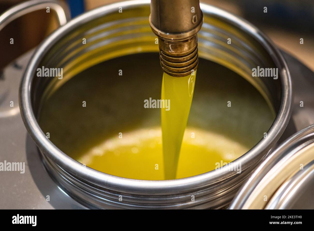 Fresh extra virgin olive oil pouring into tank at a cold-press factory after the olive season harvesting Stock Photo
