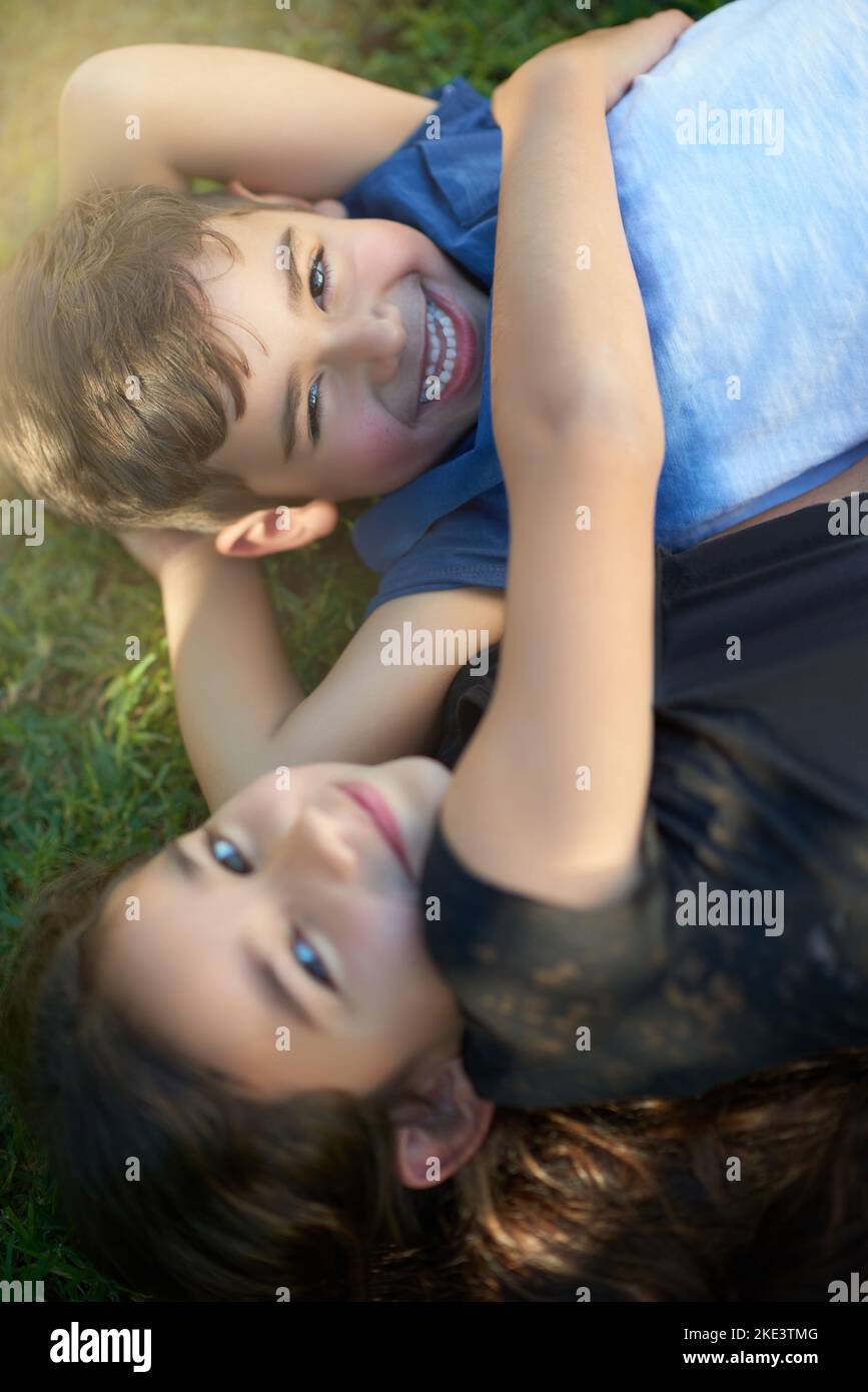 Hes my brother and my best friend. Portrait of a pair of young siblings hugging each other while lying on the grass outside their home. Stock Photo