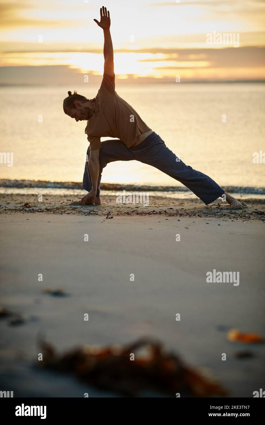 Treat your body and soul to some yoga. a man practicing the triangle ...