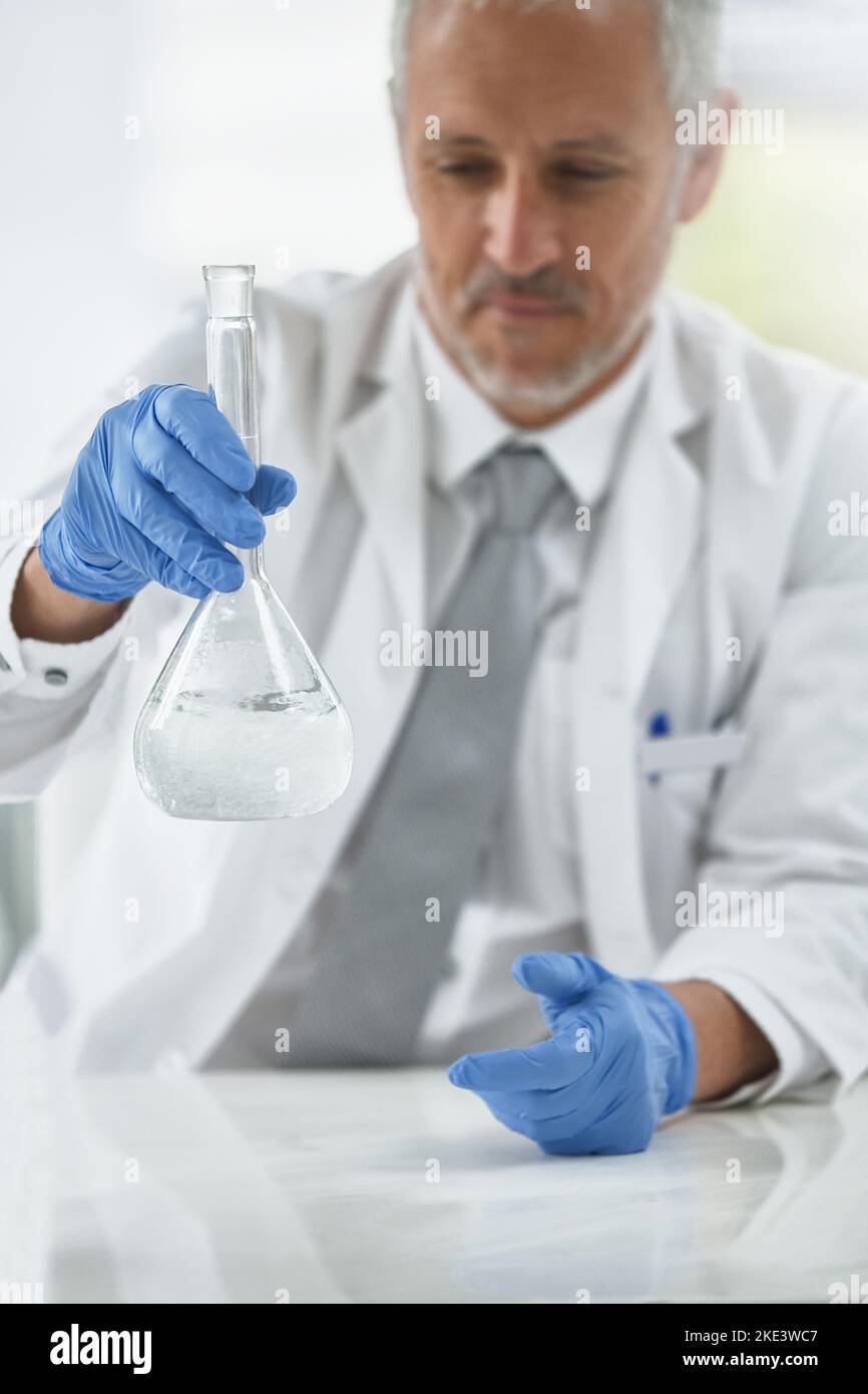 Lets mix things up a bit. a researcher working with beakers in a lab. Stock Photo