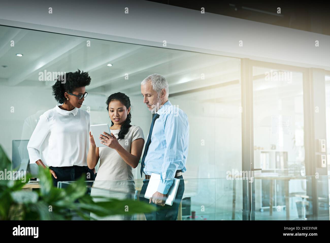 One persons strengths will cover anothers weakness, thats teamwork. a business team using a digital tablet while having an informal meeting. Stock Photo