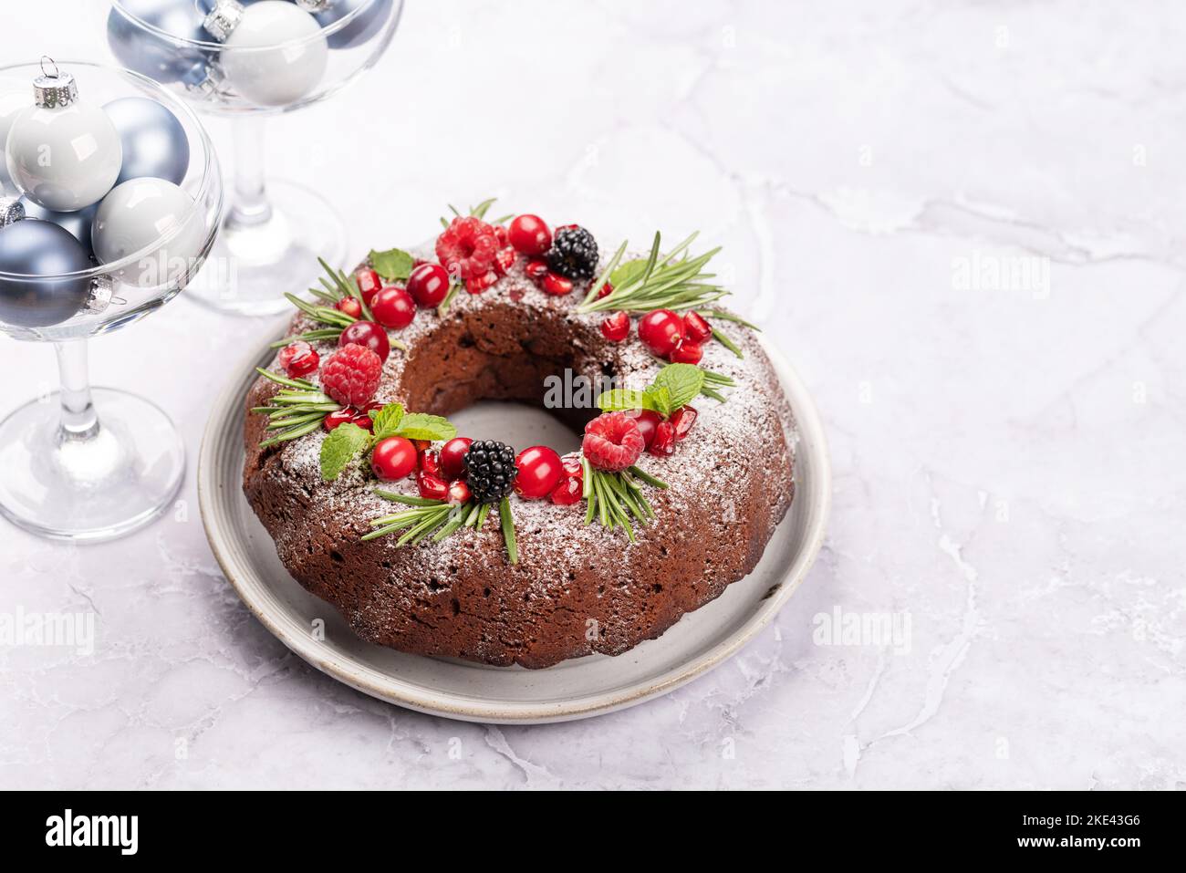Christmas cake decorated with pomegranate seeds, cranberries and rosemary. With copy space Stock Photo