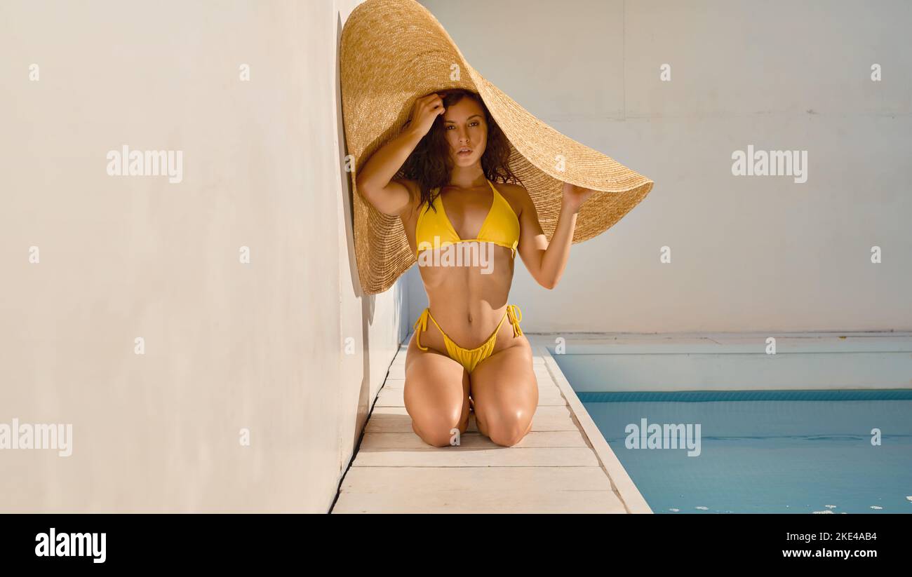 Attractive woman hiding from hot sun under big straw hat Stock Photo