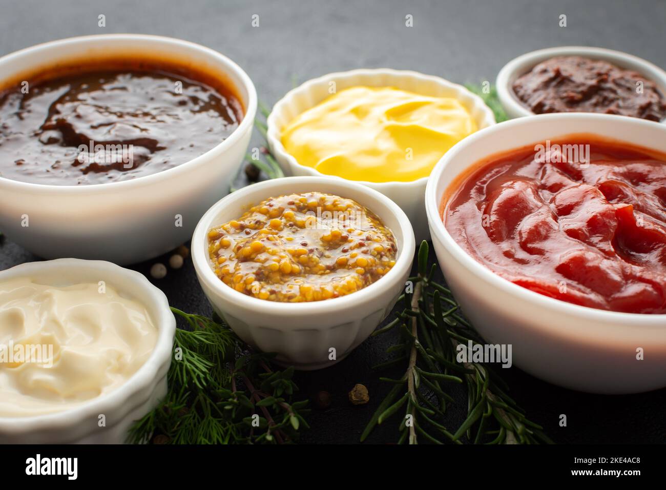 Different types of sauces in bowls with seasonings, rosemary and dill
