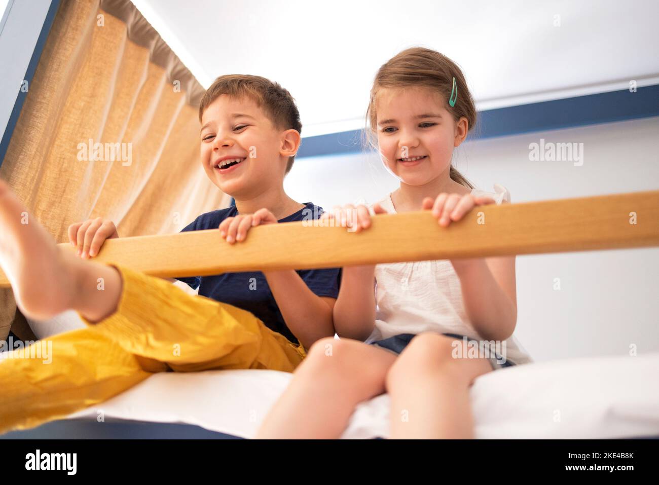 Caucasian little sibling are sitting on the bunk bed and looking to camera with big smile. Concept of love, relation, bonding friendship of brother an Stock Photo