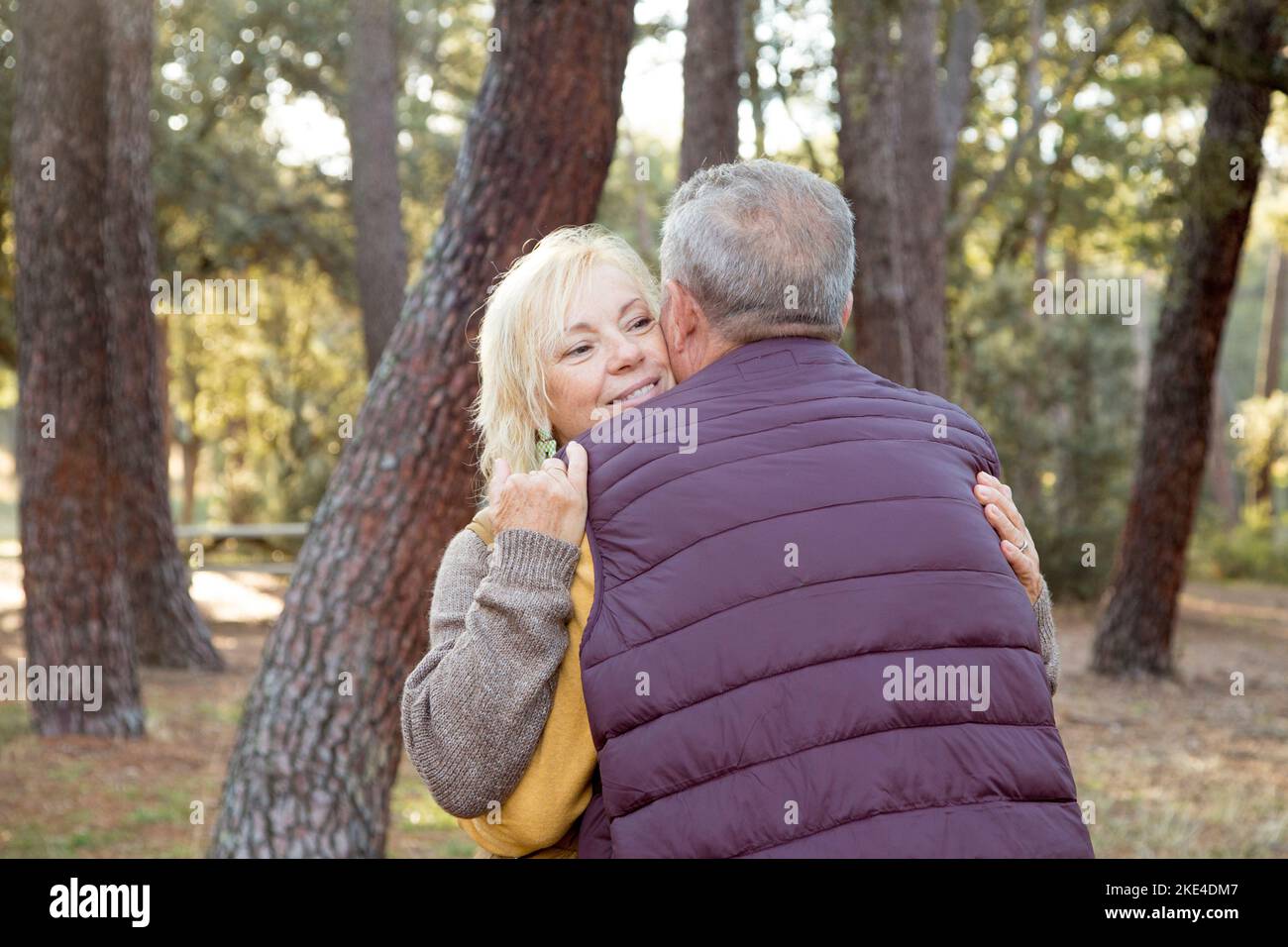 Smiling woman embracing her couple in a forest Stock Photo