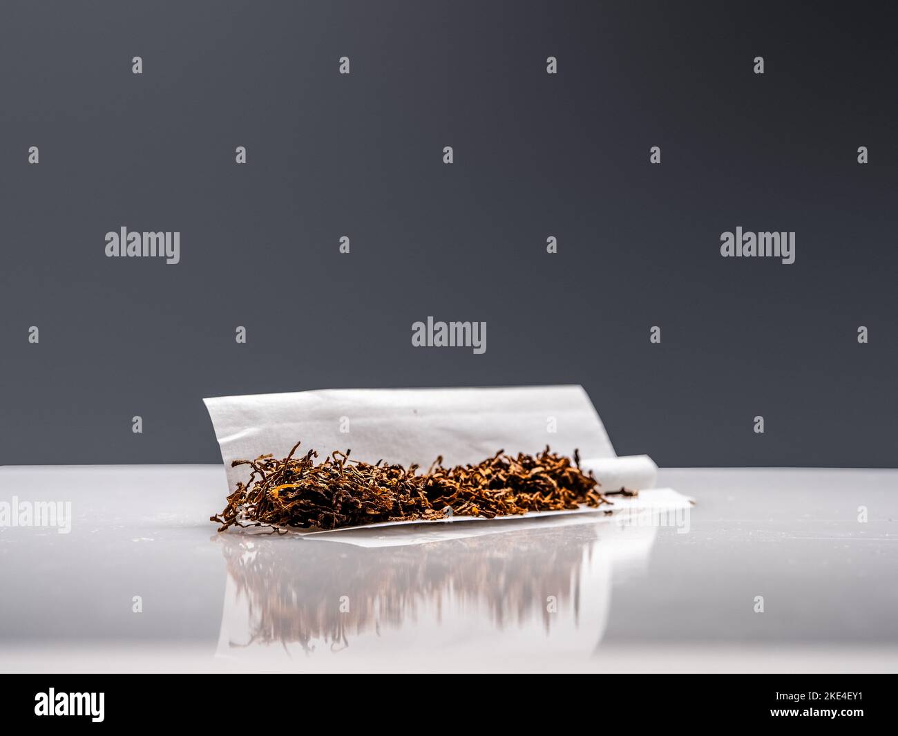 A closeup shot of Tobacco on rolling paper and filter on the grey  background Stock Photo
