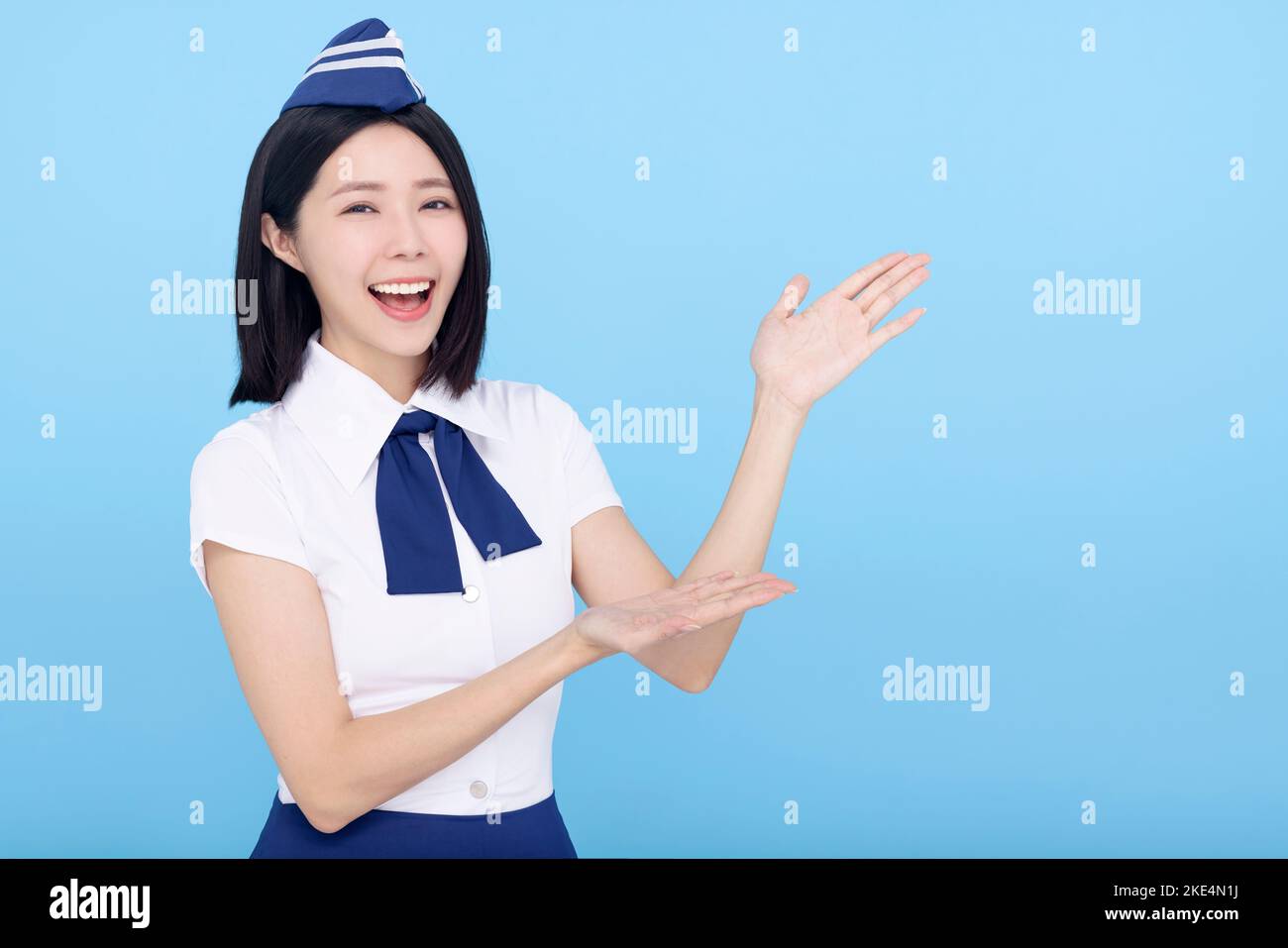 Beautiful stewardess showing something on blue background Stock Photo