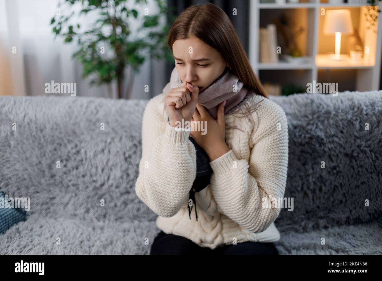 Sick woman coughing on couch Stock Photo