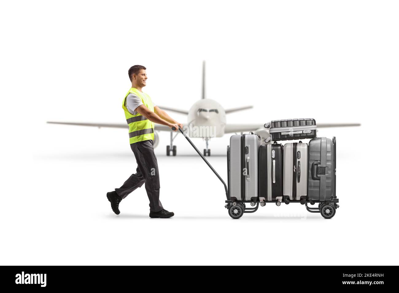 Airport worker pushing a luggage cart with suitcases in front of an airplane isolated on white