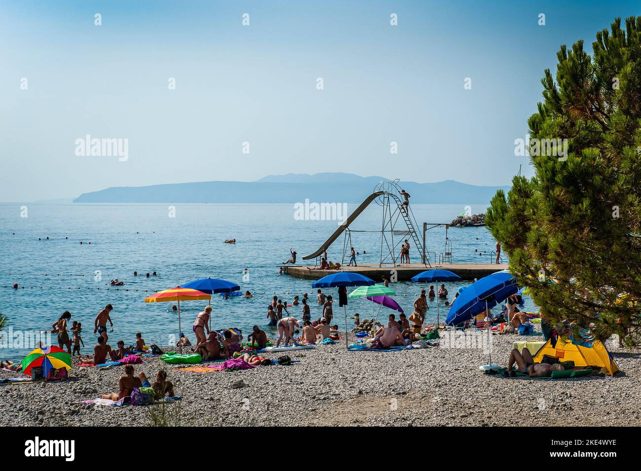 Beach on the Adriatic, Croatia, sunbathers on beach with slide shoot in the background calm day in summer Stock Photo