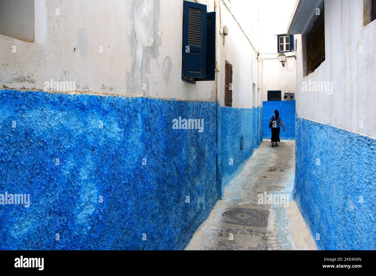 Pedestrian in a narrow street painted in blue and white, Kasbah of the Udayas, Kasbah of the Oudaias, Rabat, Morocco Stock Photo