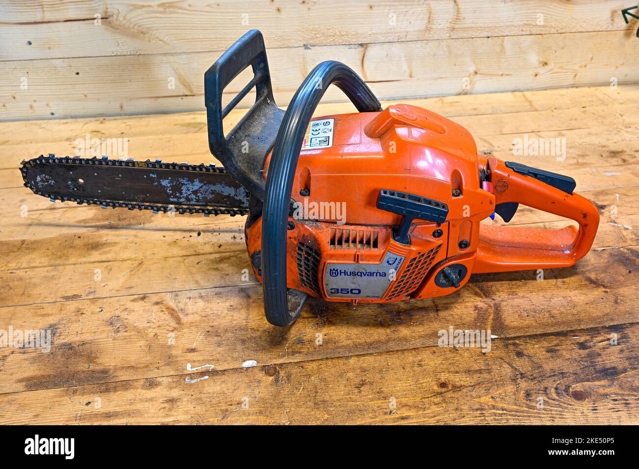 Orange chainsaw Husqvarna 350 standing on wooden workbench Stock Photo