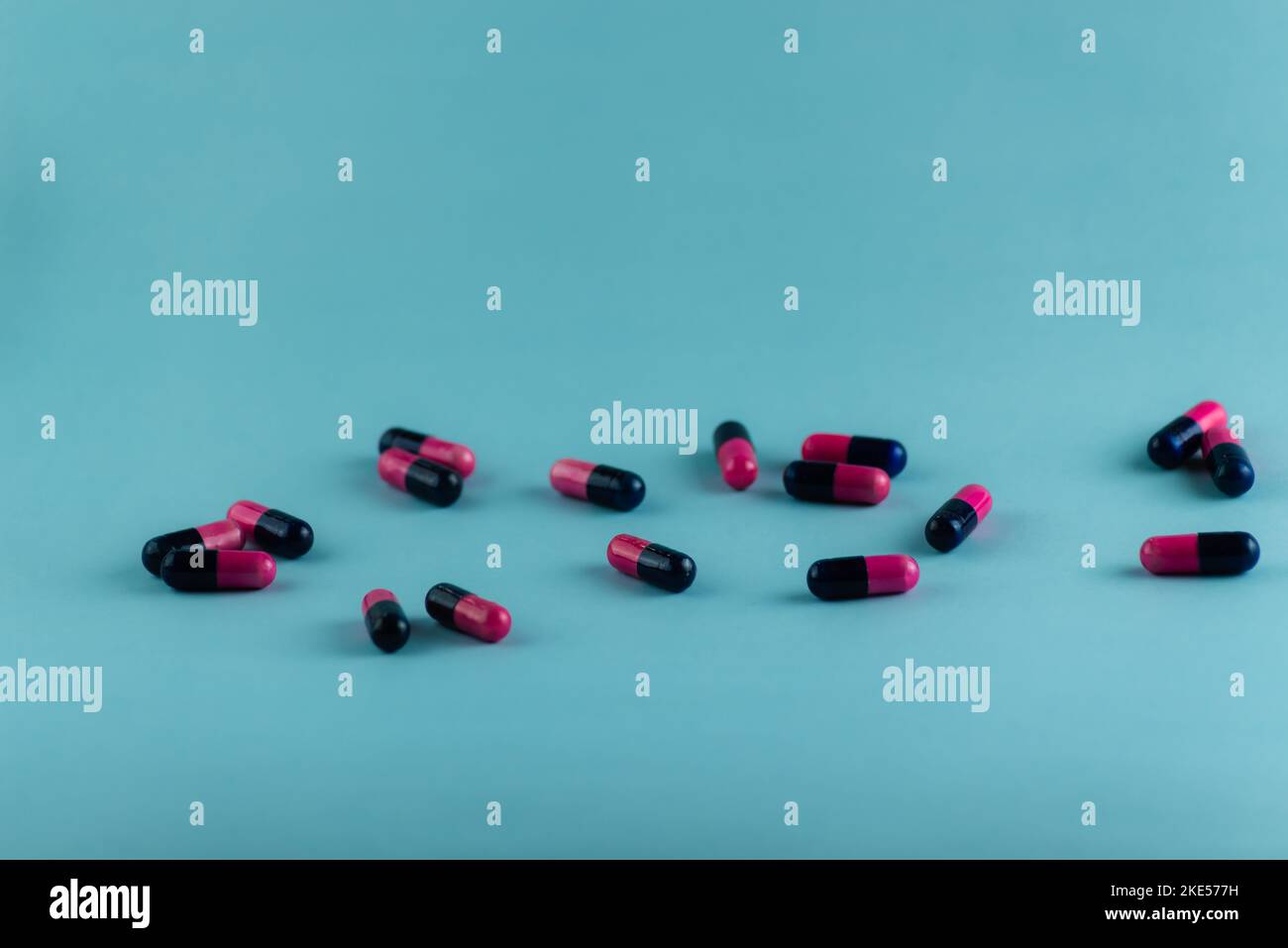 Simple pile of pink and black pills. Medicines, pills stacked on blue