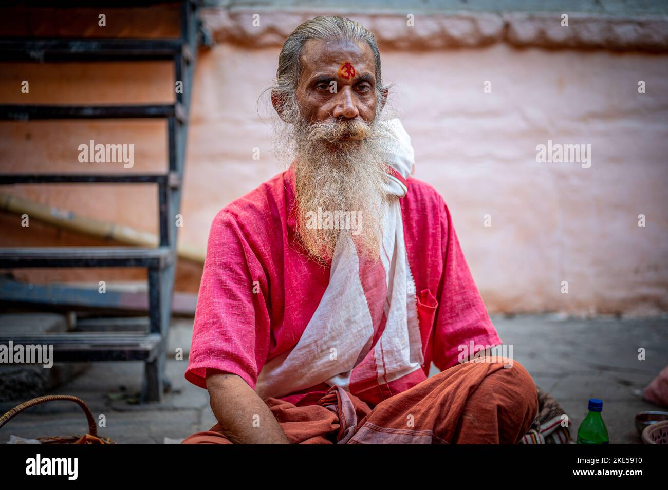 An Indian Godman in a traditional costume sitting on a sidewalk on the