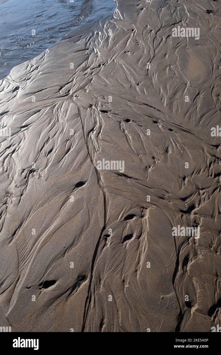 Rivulets caused by retreating tide in soft sand on a beach Stock Photo