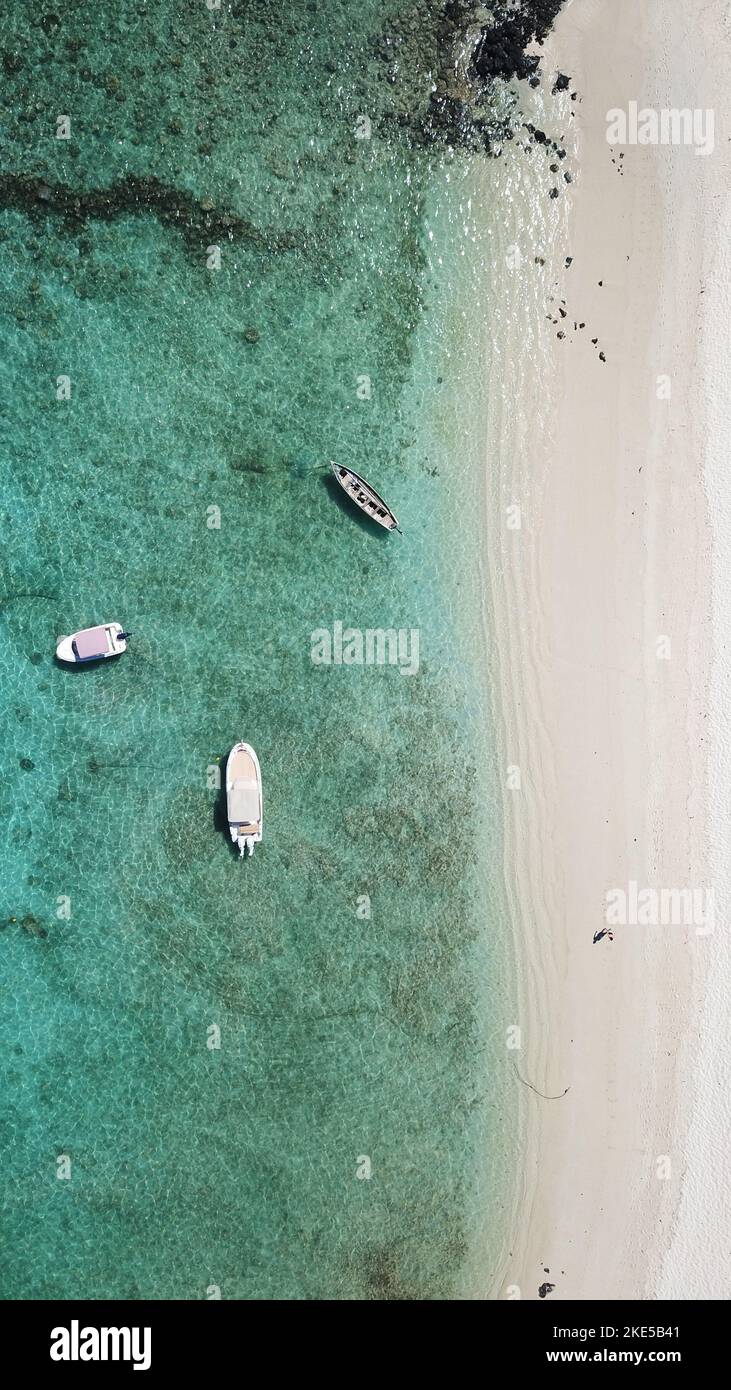 A vertical aerial top view of a seashore with moored boats on a beach ...