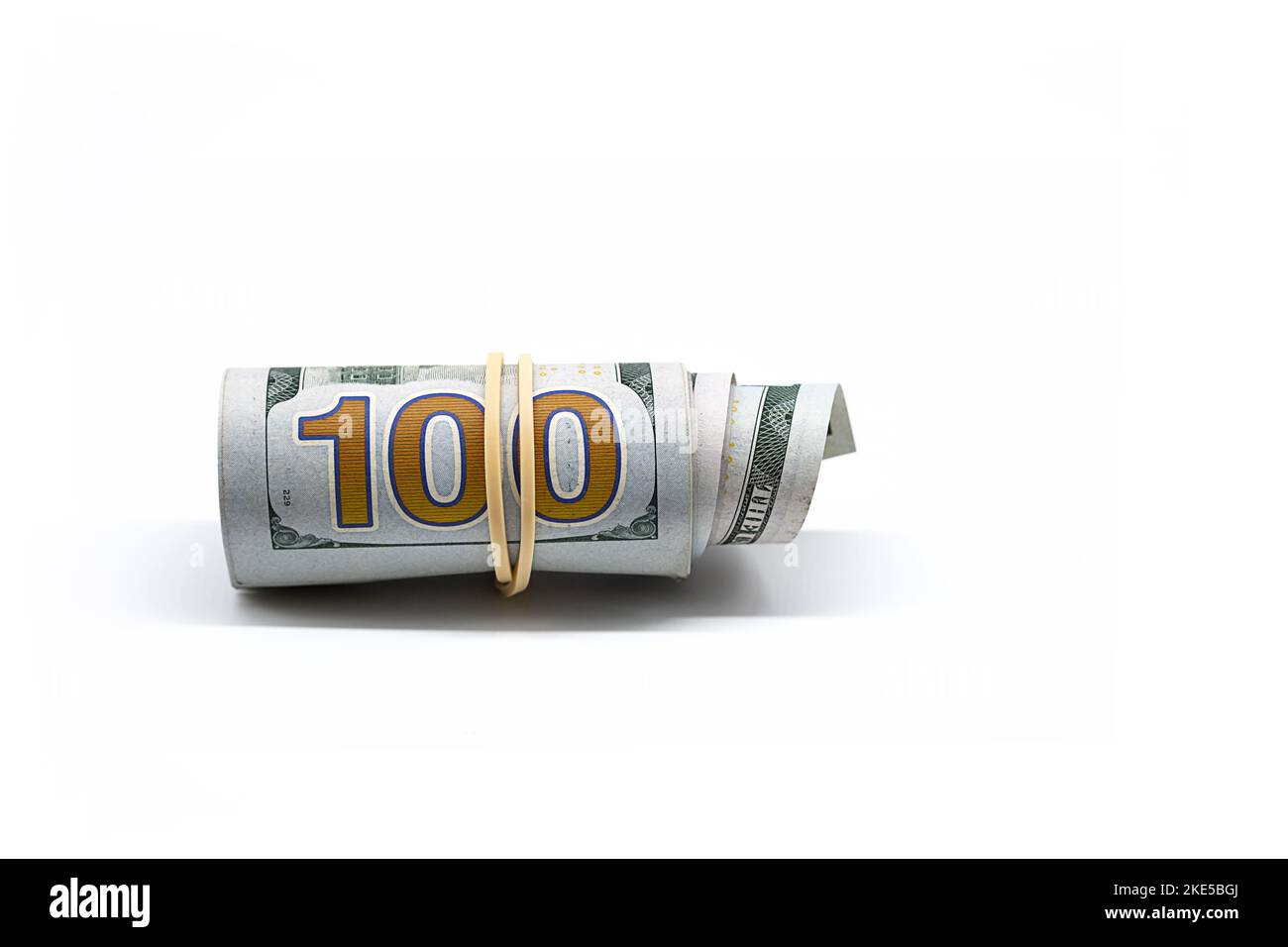 Rolled up one hundred dollar bills on white. Roll of U.S. paper ...