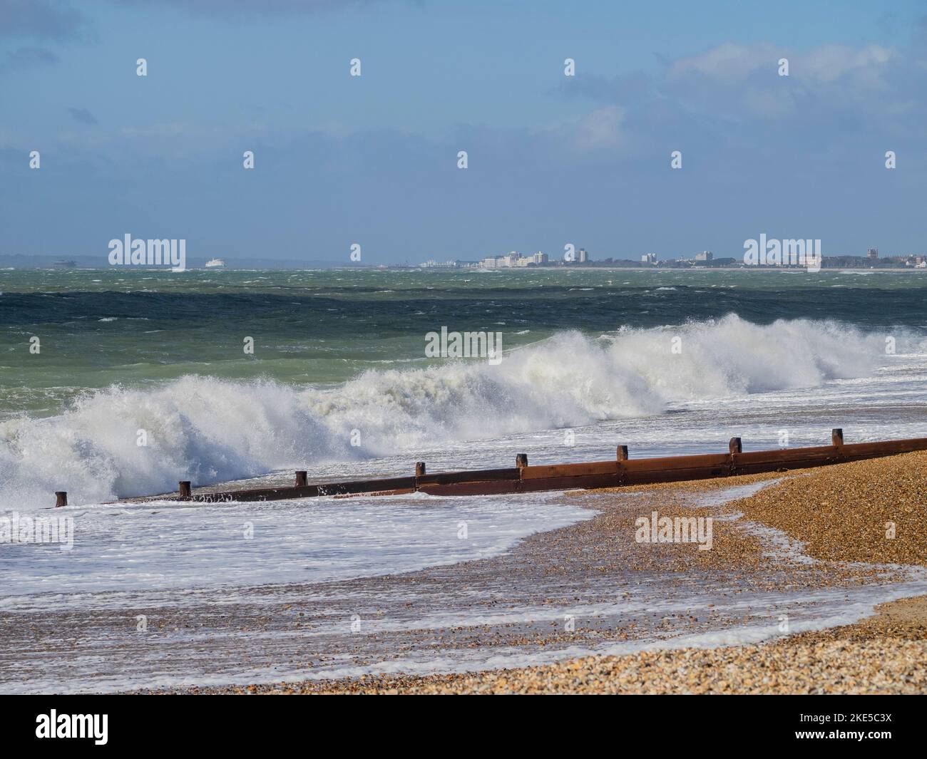 Waves crashing on to beach at Hayling Island with Southsea and Isle of Wight in the background, Hampshire, England Stock Photo