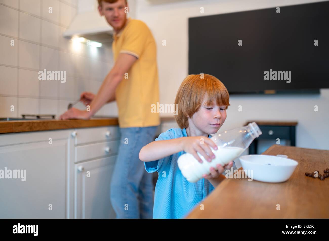 Little boy puring milk from the bottle to the plate Stock Photo