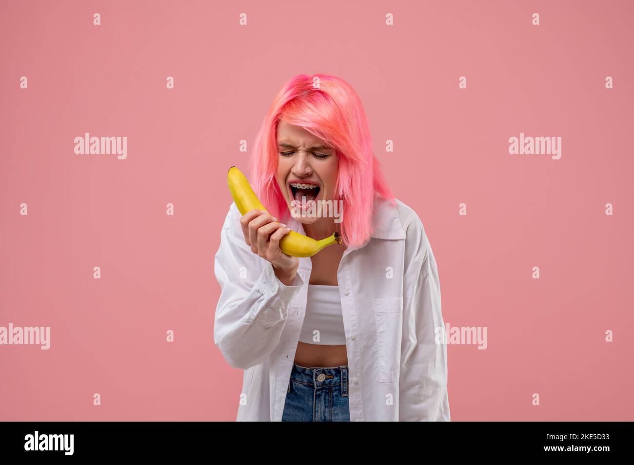 Pinkhaired girl singing into the banana mic Stock Photo Alamy