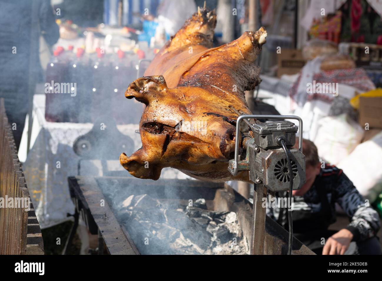 Piglet on a spit. Grilled pig at the street food festival. Roasted pig on the rack. Food. Stock Photo
