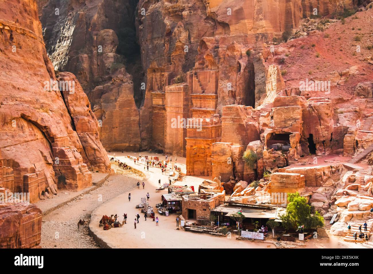 Tourist walk by caves of tombs in ancient city of Petra, Jordan. It is know as the Loculi. Petra has led to its designation as UNESCO World Heritage S Stock Photo