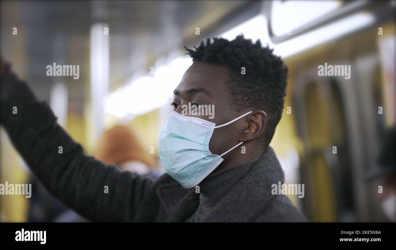 Black man standing at metro subway wearing covid19 face mask during
