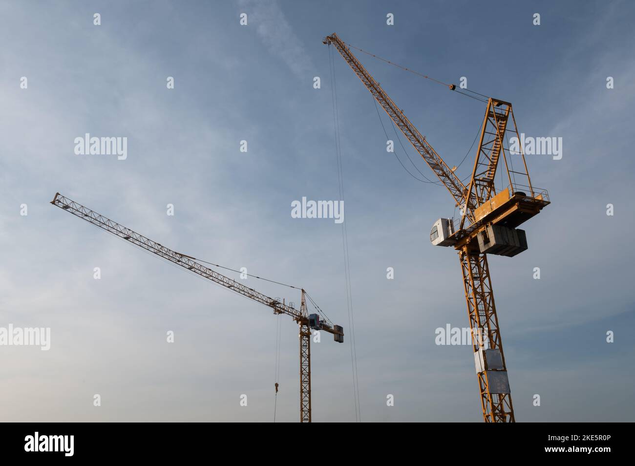 Construction site with two yellow cranes against blue sky Stock Photo