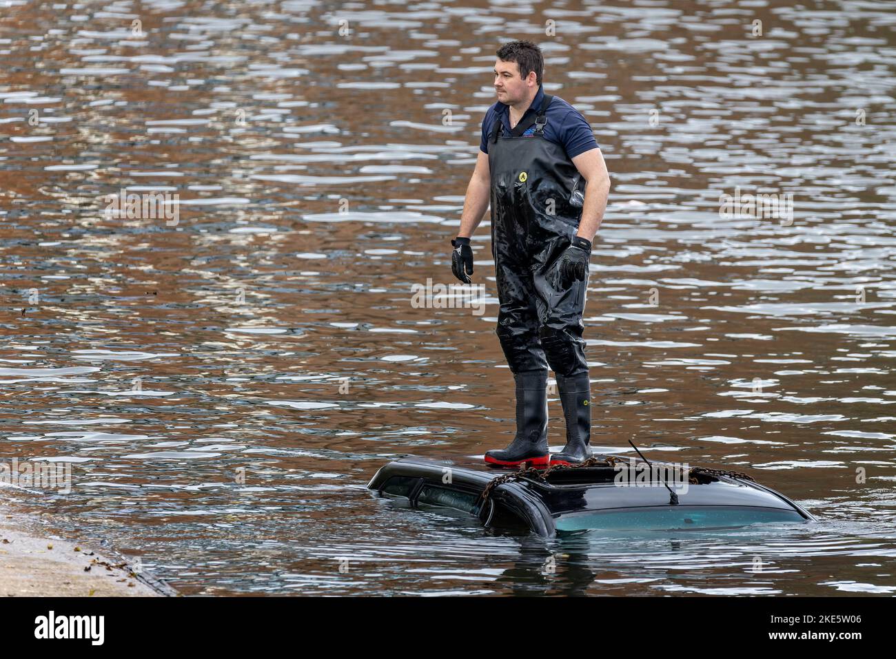 Rescue worker standing on top of roof of submerged car driven into River Avon by accident in Stratford upon Avon, Warwickshire, UK on 8 November 2022 Stock Photo