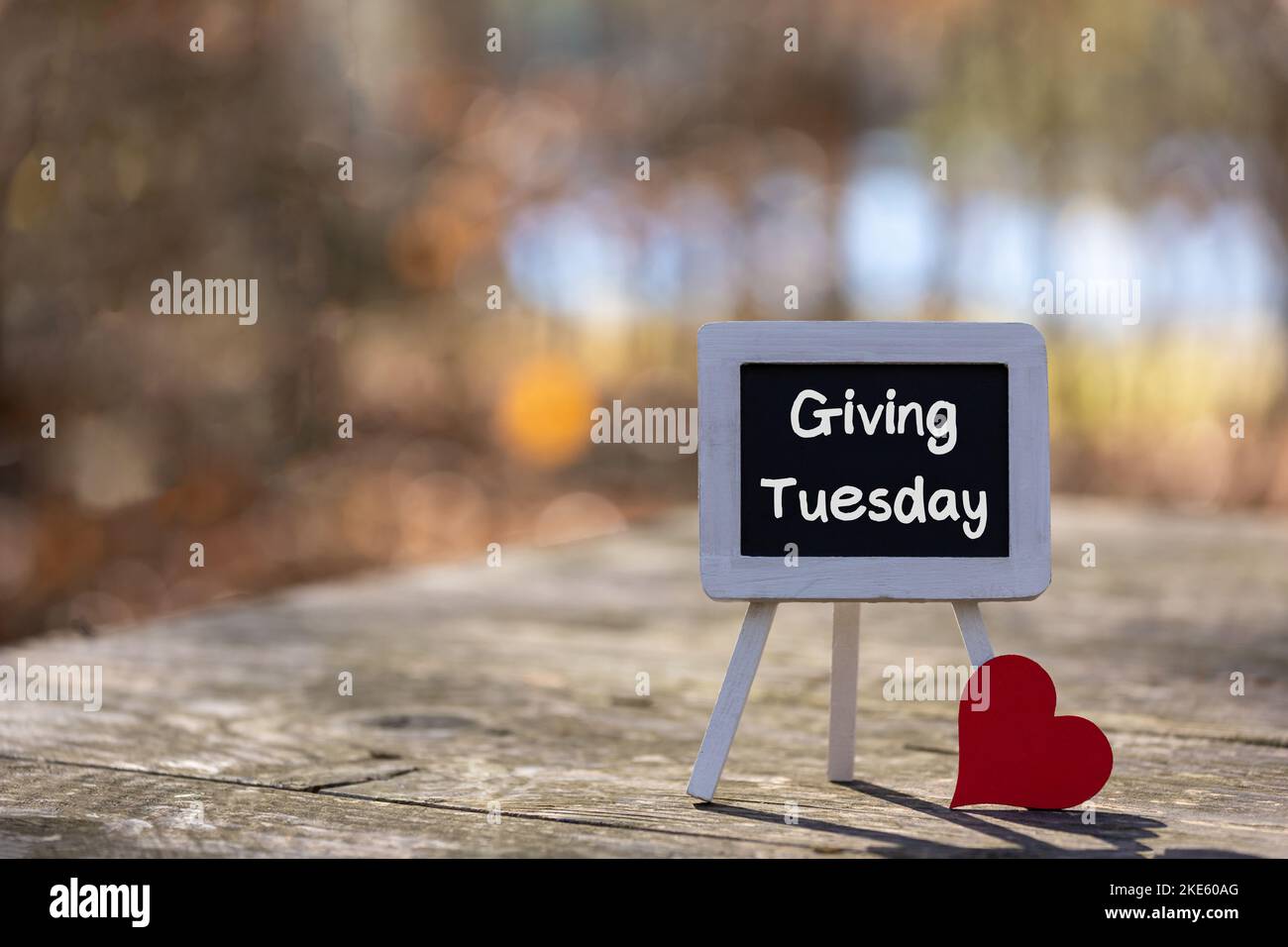 Giving Tuesday text message on chalkboard easel with red heart soft bokeh background copy space Stock Photo